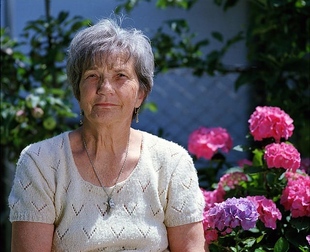 Older woman smiling on a sunny day in her garden